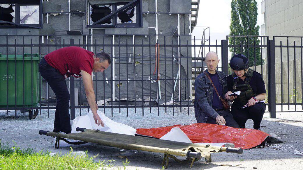 Мужчина читает молитву, держа за руку своего 13-летнего сына, погибшего во время сегодняшнего обстрела в Харькове